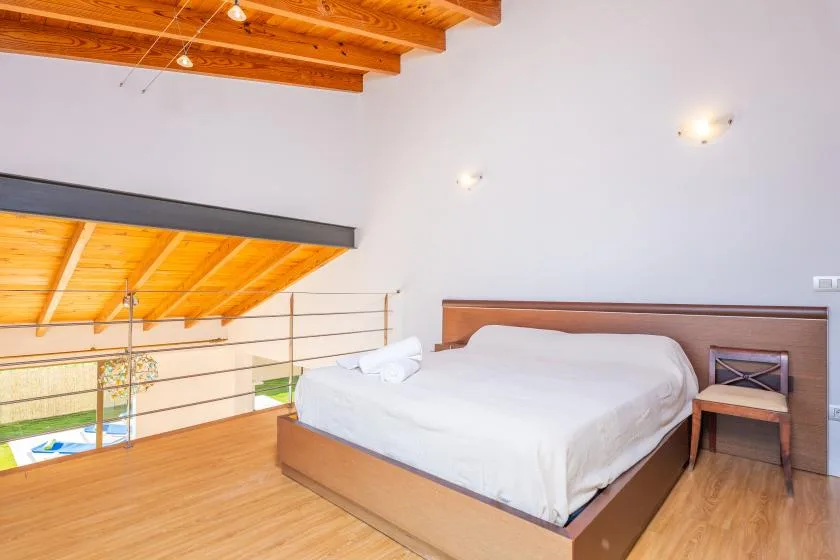 A bedroom with a bed beneath a sloped wooden ceiling.