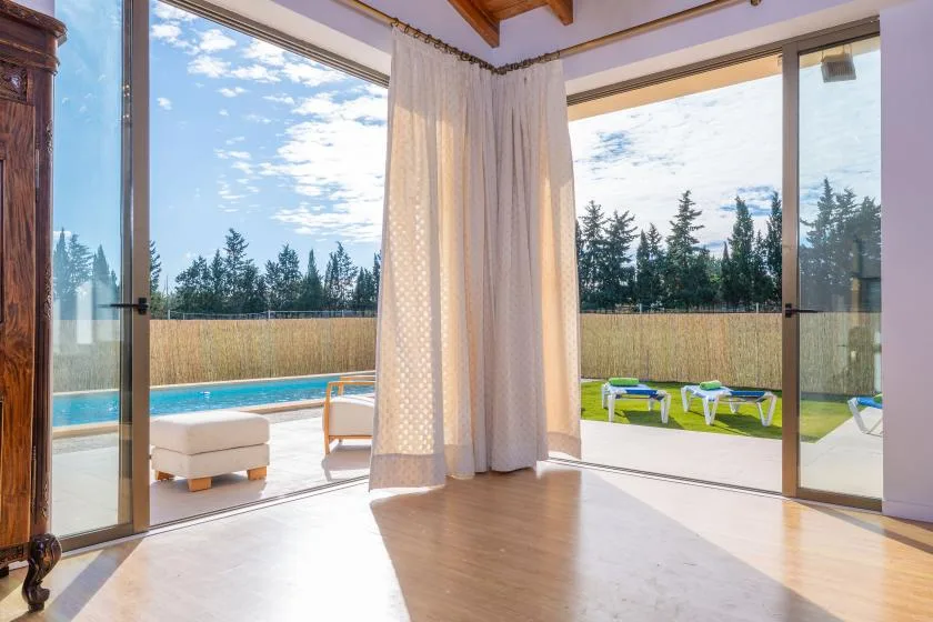 A bright room opens onto a poolside patio through large glass doors.