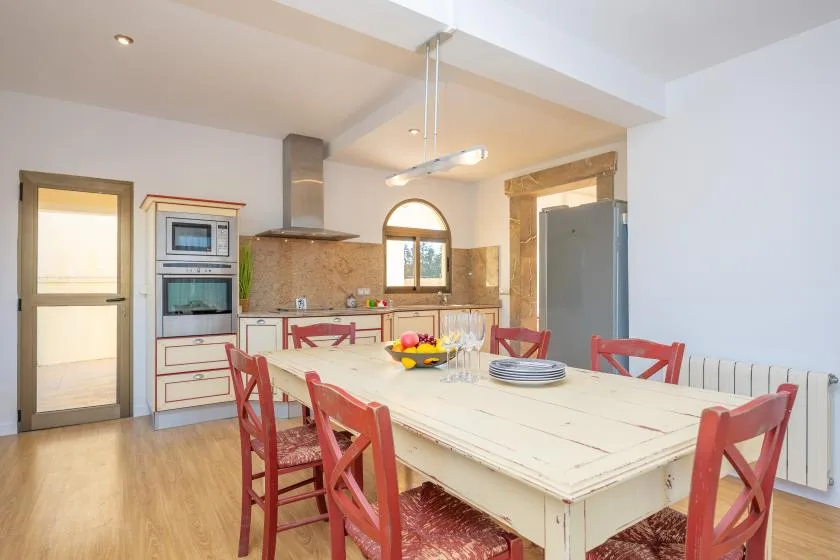 A bright kitchen and dining area with a large table and red seating.
