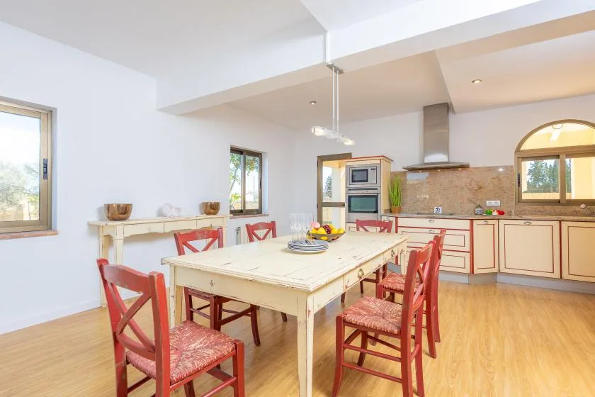 A bright kitchen and dining area with a large table and red chairs.