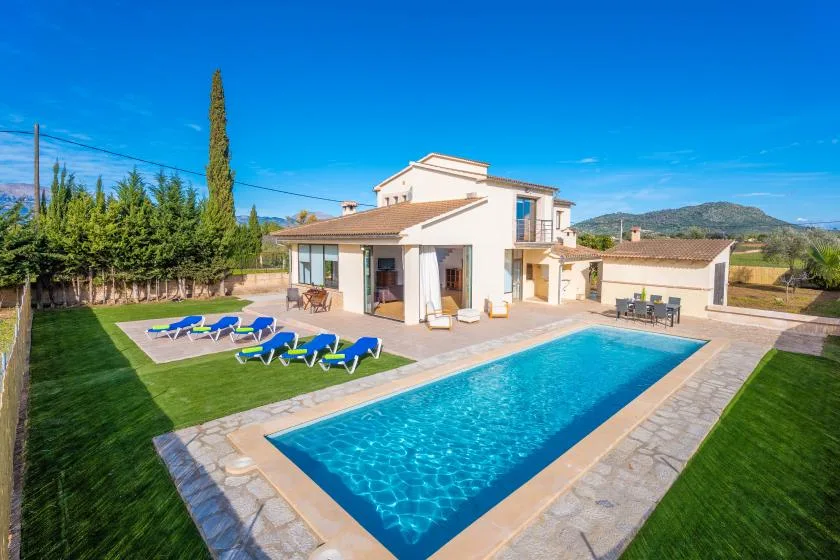 A house and outdoor swimming pool sit beside a lawn and patio.
