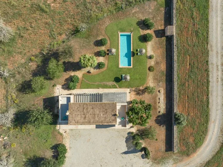 An aerial view shows a rectangular swimming pool beside a house and landscaped yard.