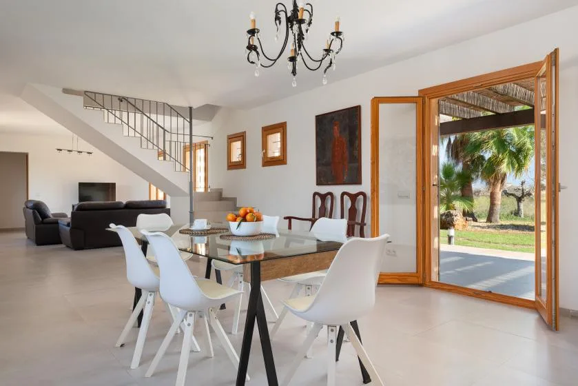 A bright dining area with a glass table and an open doorway to the patio.