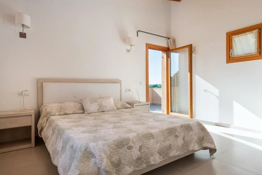 A bedroom with a large bed beside an open glass door.