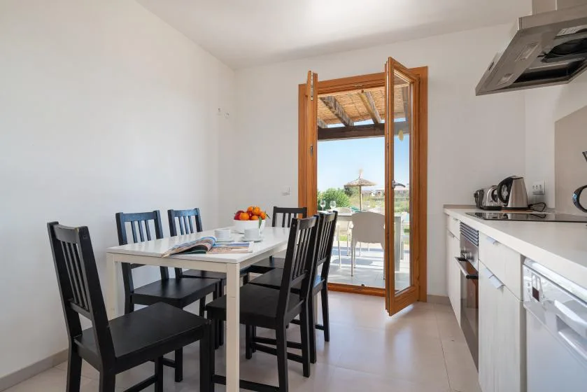 A dining area with a table and chairs beside an open balcony door.