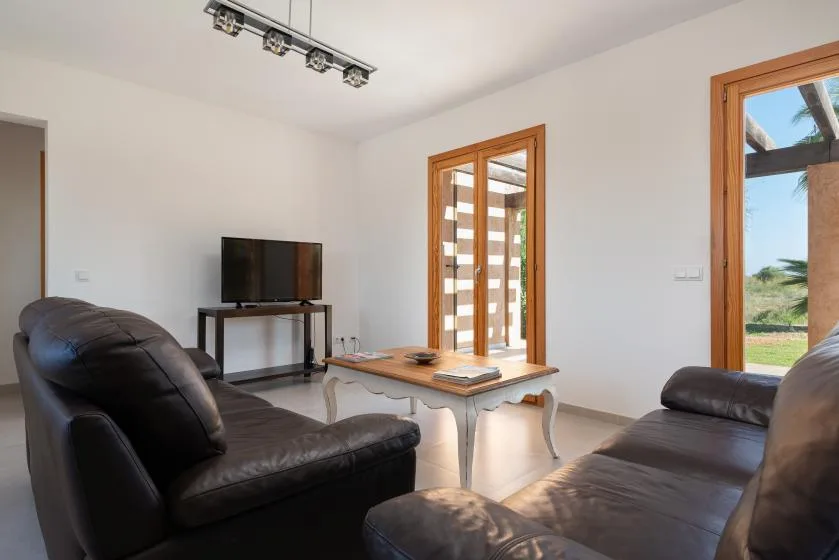 A living room with dark seating, a television, and a low table.