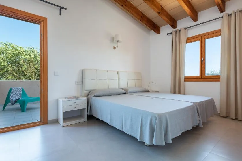 A bedroom with a large bed, bedside table, and exposed wooden ceiling beams.