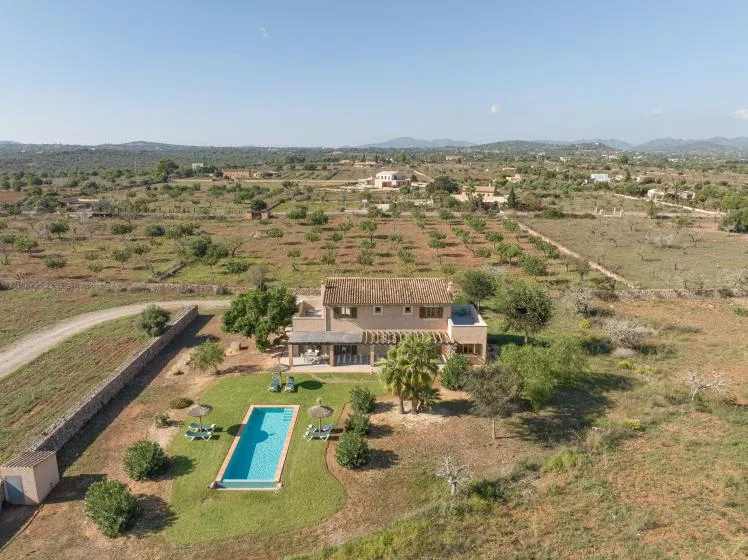 Aerial view of a rural house with a swimming pool and surrounding fields.