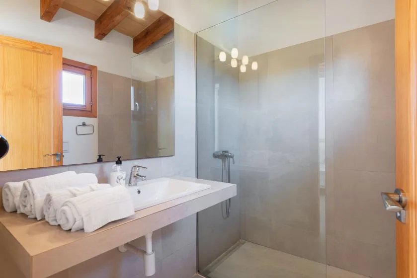 A bright bathroom with a sink, mirror, and glass shower.
