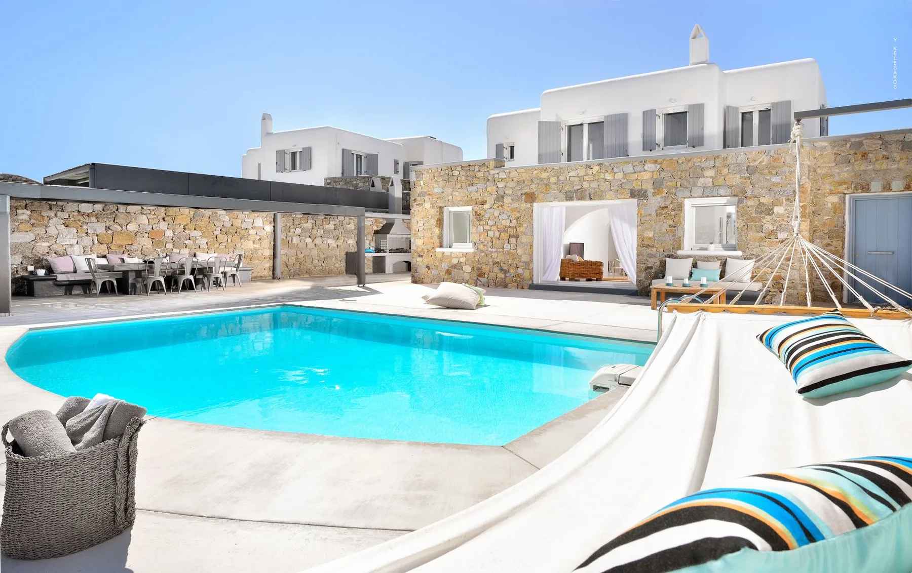 An outdoor pool beside a stone-faced building, with striped cushions on loungers.