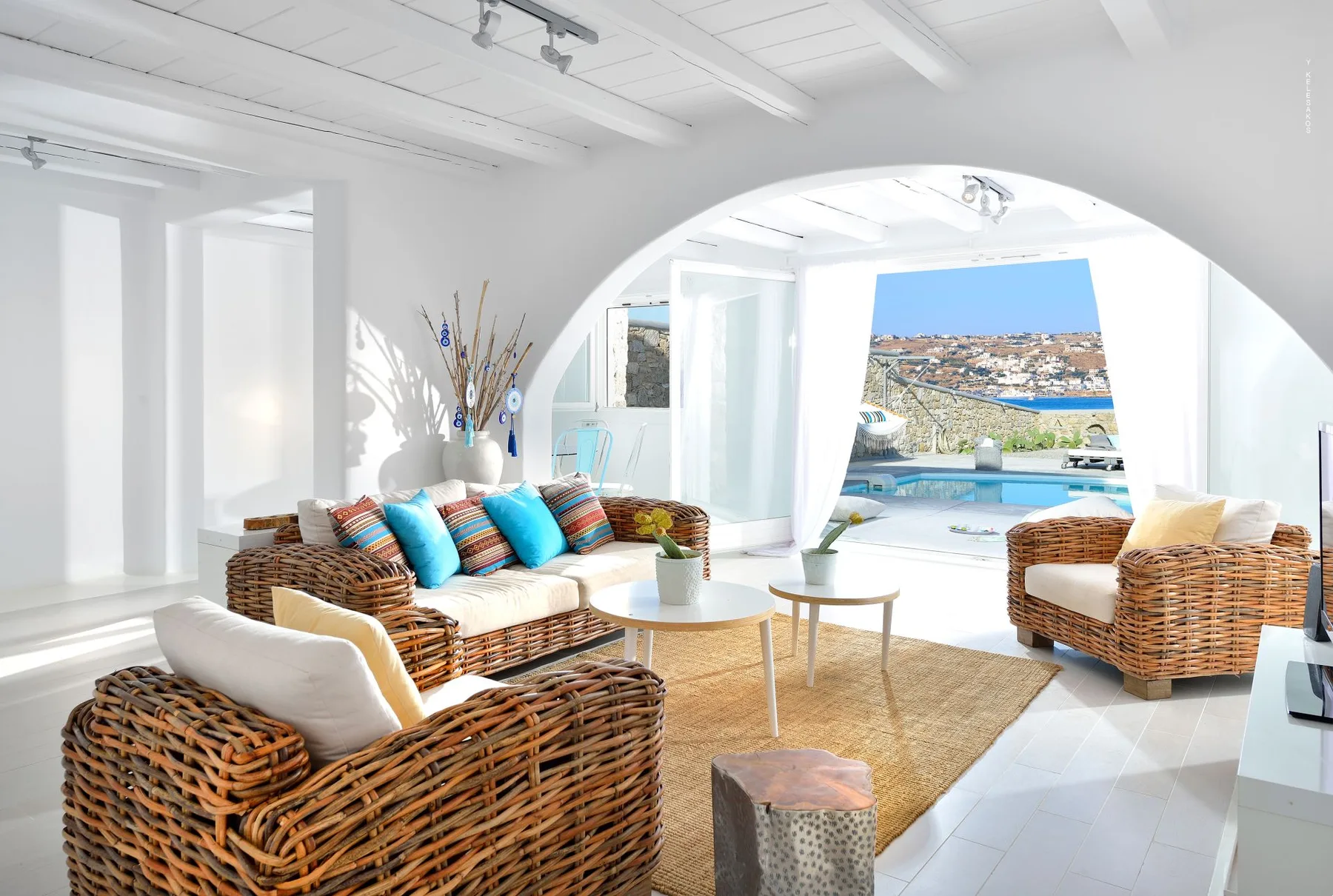 A bright living room with woven seating and a view through an arched opening.