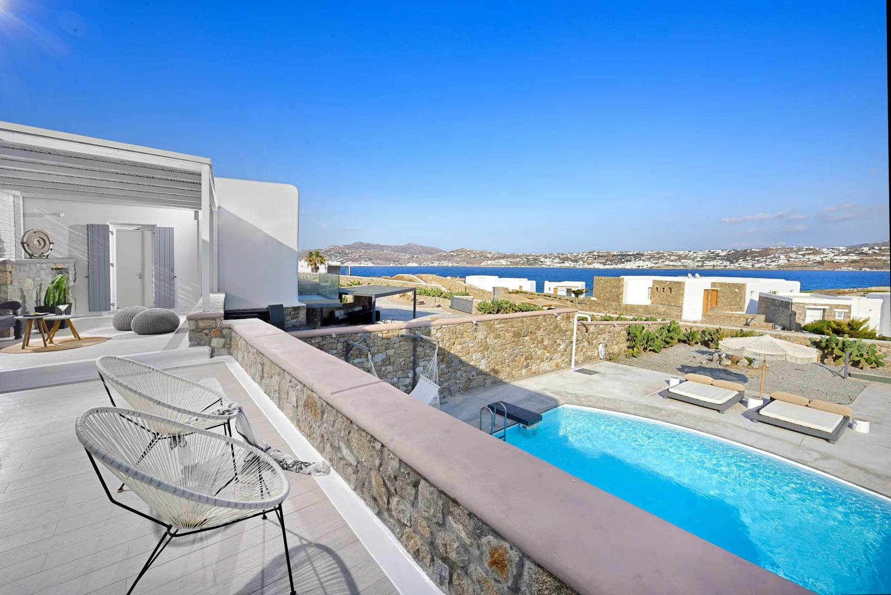 A rooftop terrace overlooks a swimming pool and the surrounding coastal landscape.
