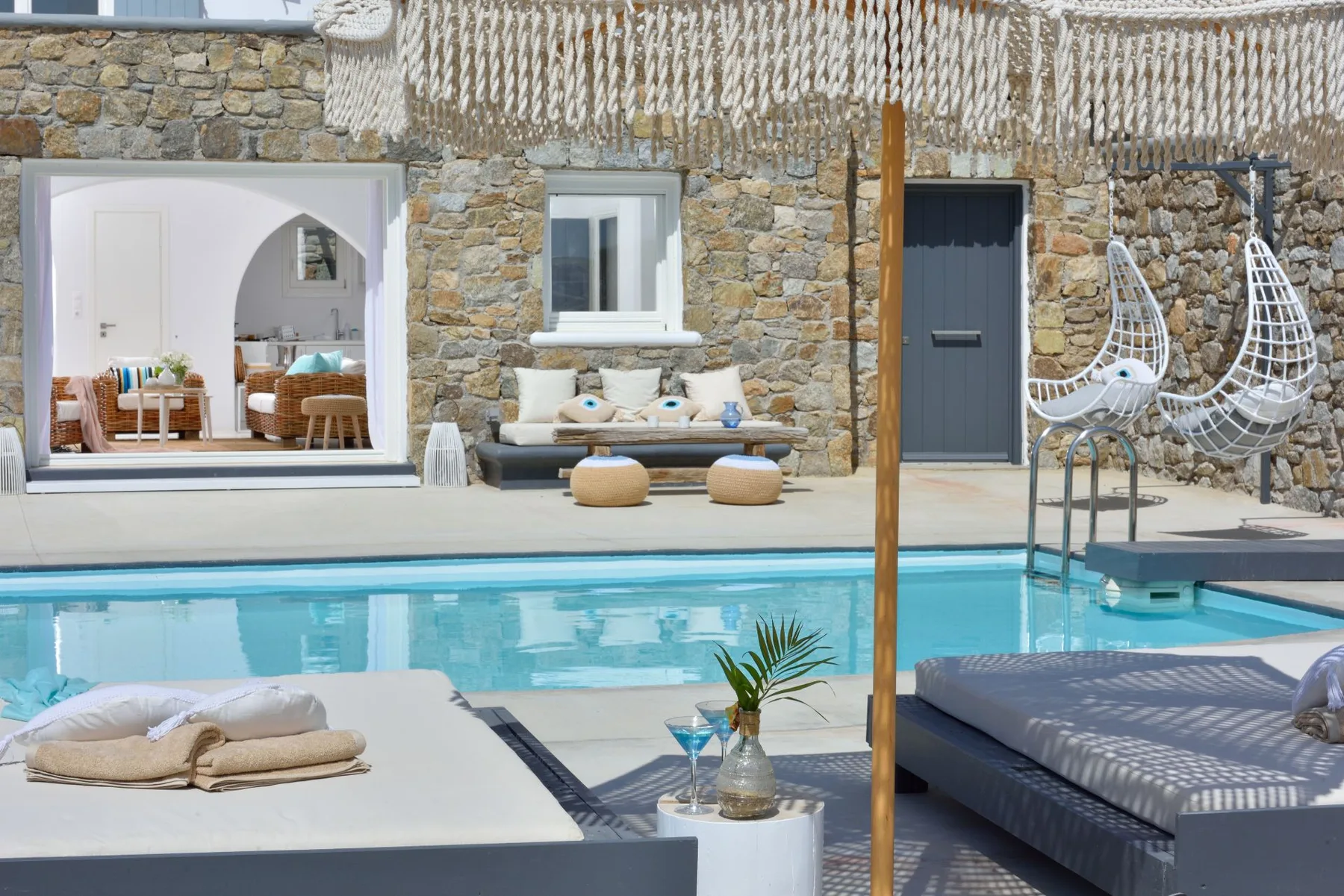 A swimming pool and sun loungers sit beside a stone-walled patio.