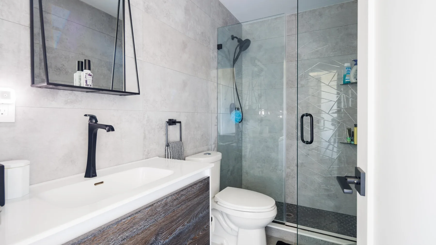 A bright bathroom with a long vanity, toilet, and glass-enclosed shower.