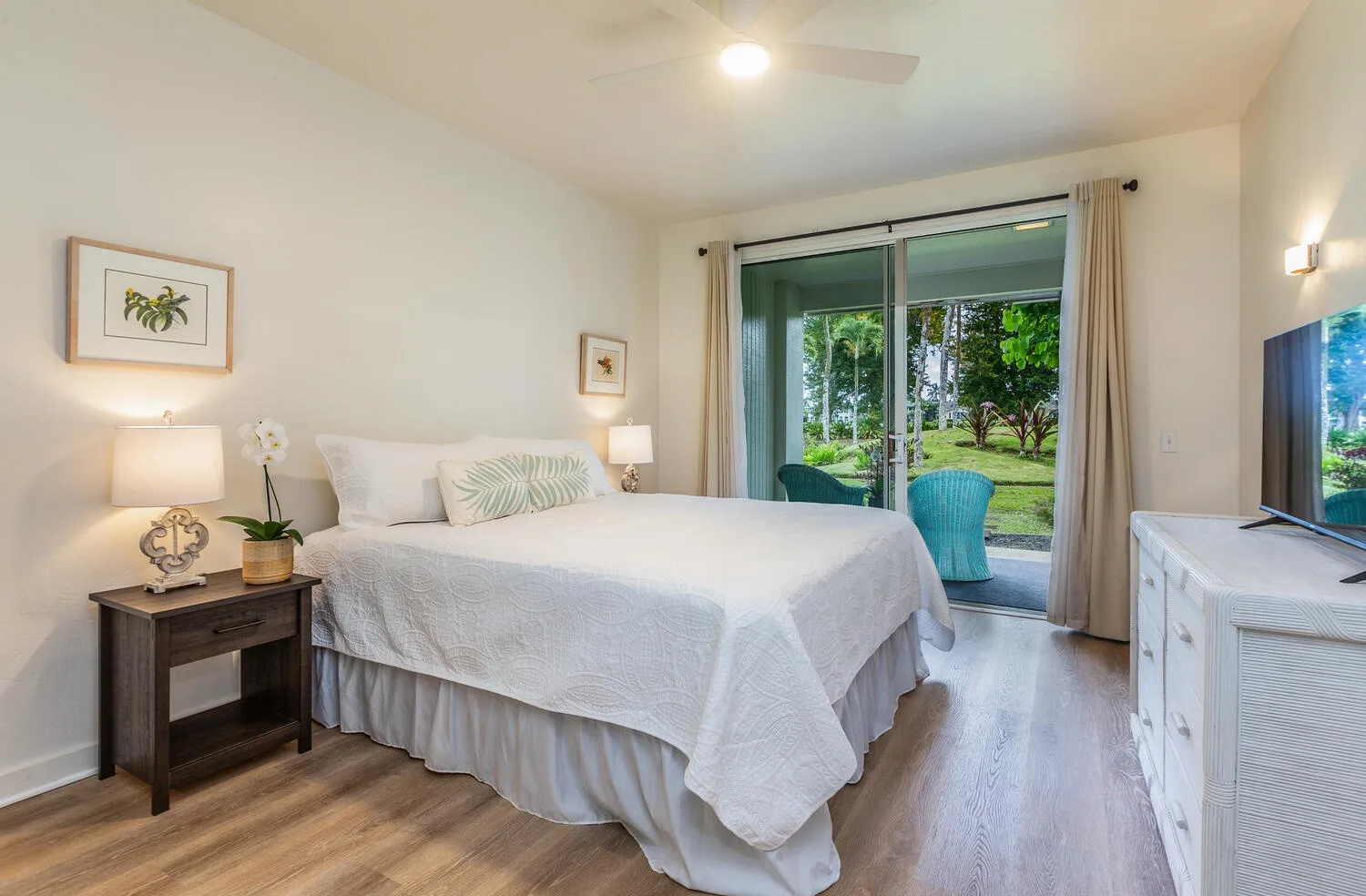 Un dormitorio luminoso con una cama junto a puertas corredizas de vidrio que dan a un jardín.