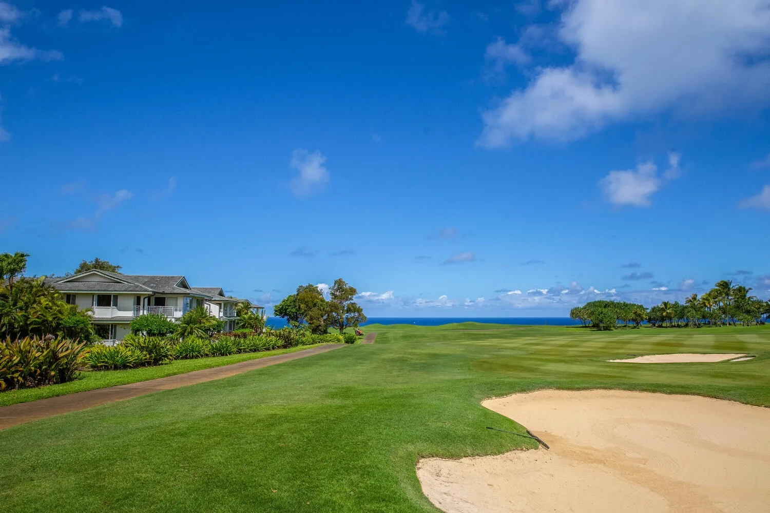 Un campo de golf con calles verdes y bunkers de arena junto al océano.