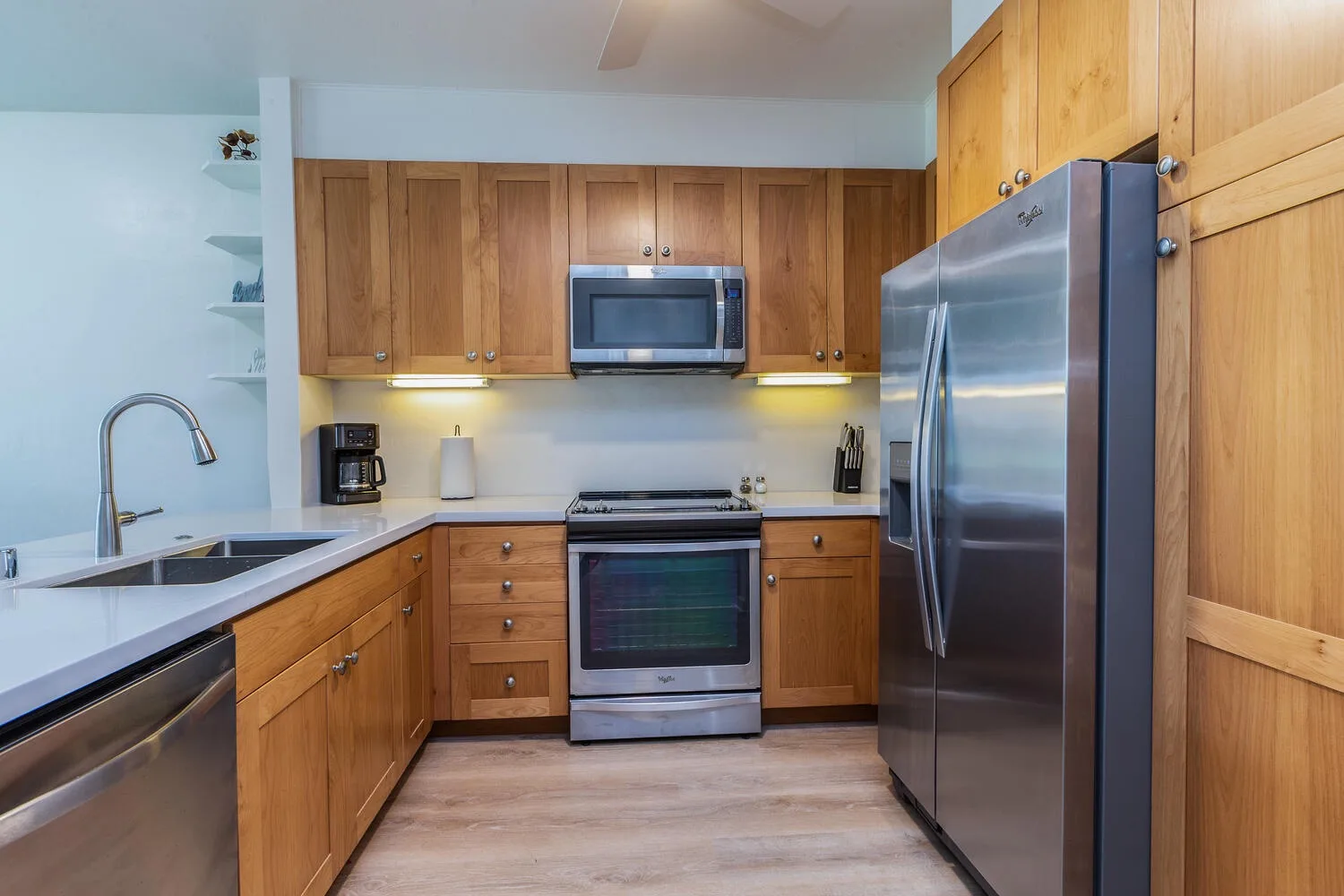 Una cocina con gabinetes de madera, electrodomésticos de acero inoxidable y un fregadero en la encimera.