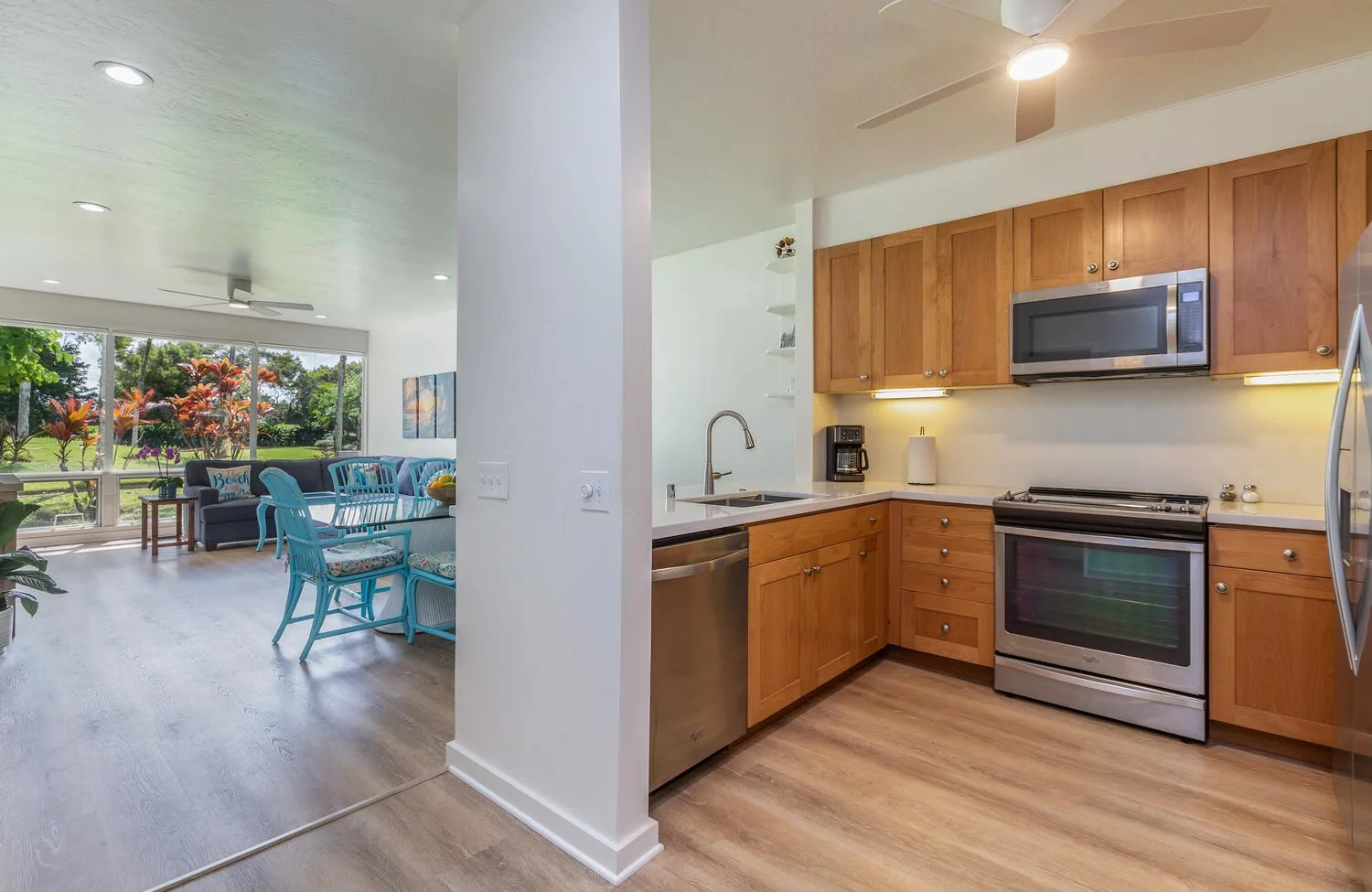 Cocina y comedor abiertos con gabinetes de madera y una mesa junto a las ventanas.