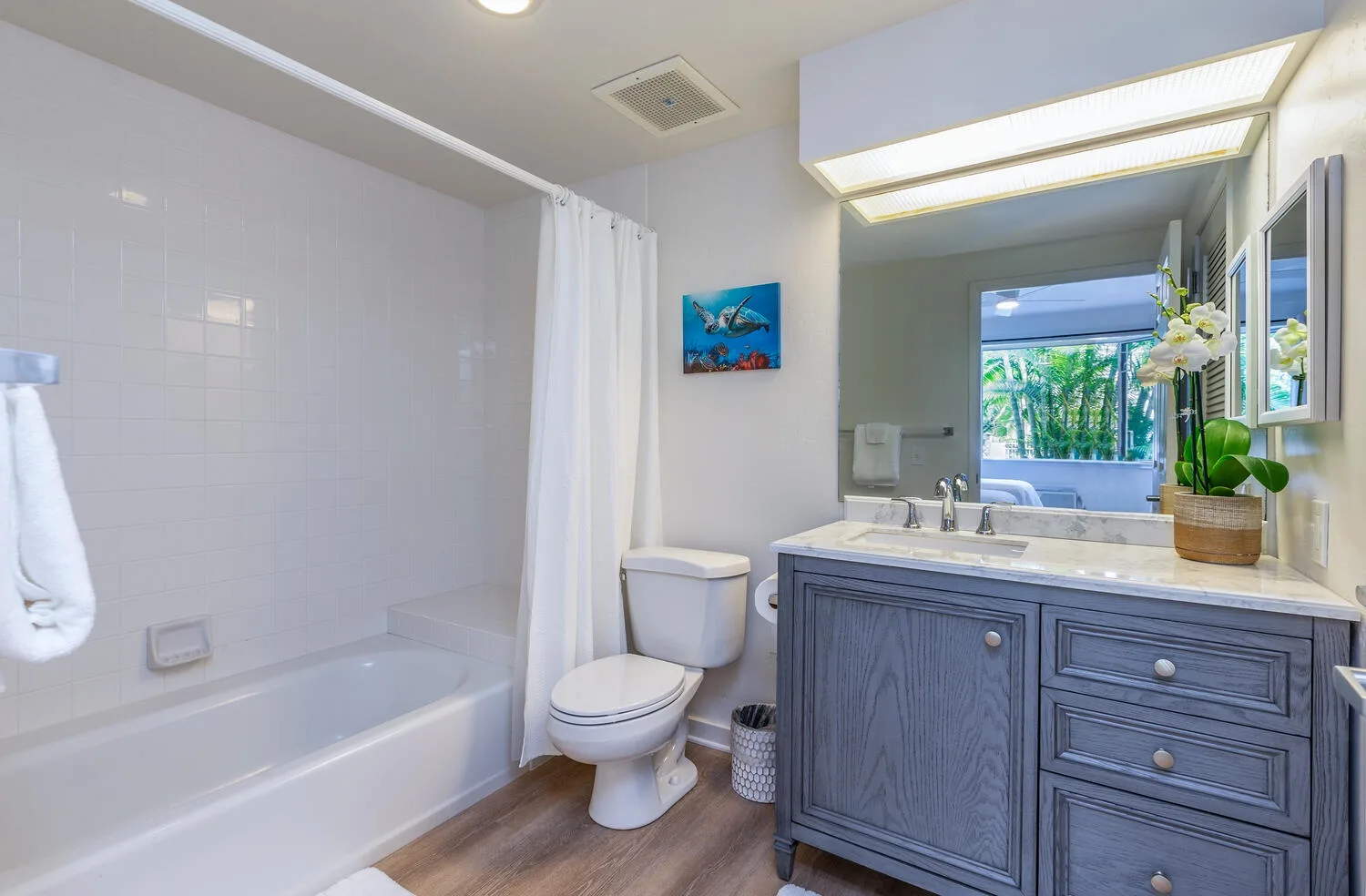 Un baño con bañera, inodoro y tocador con lavabo.