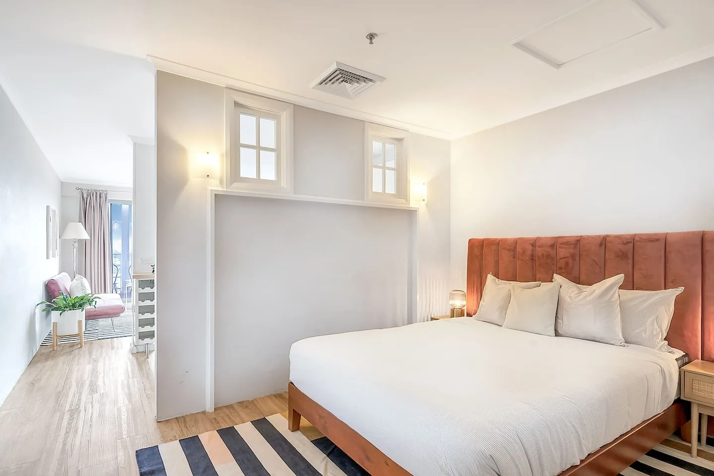 A bright bedroom features a large bed with a tufted headboard.
