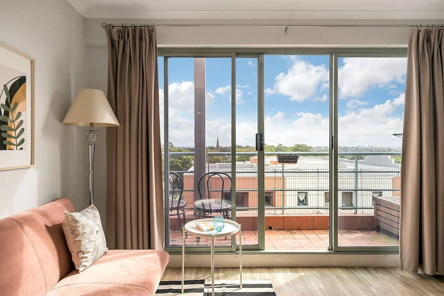 A living room with seating and a coffee table faces large glass doors and a balcony.