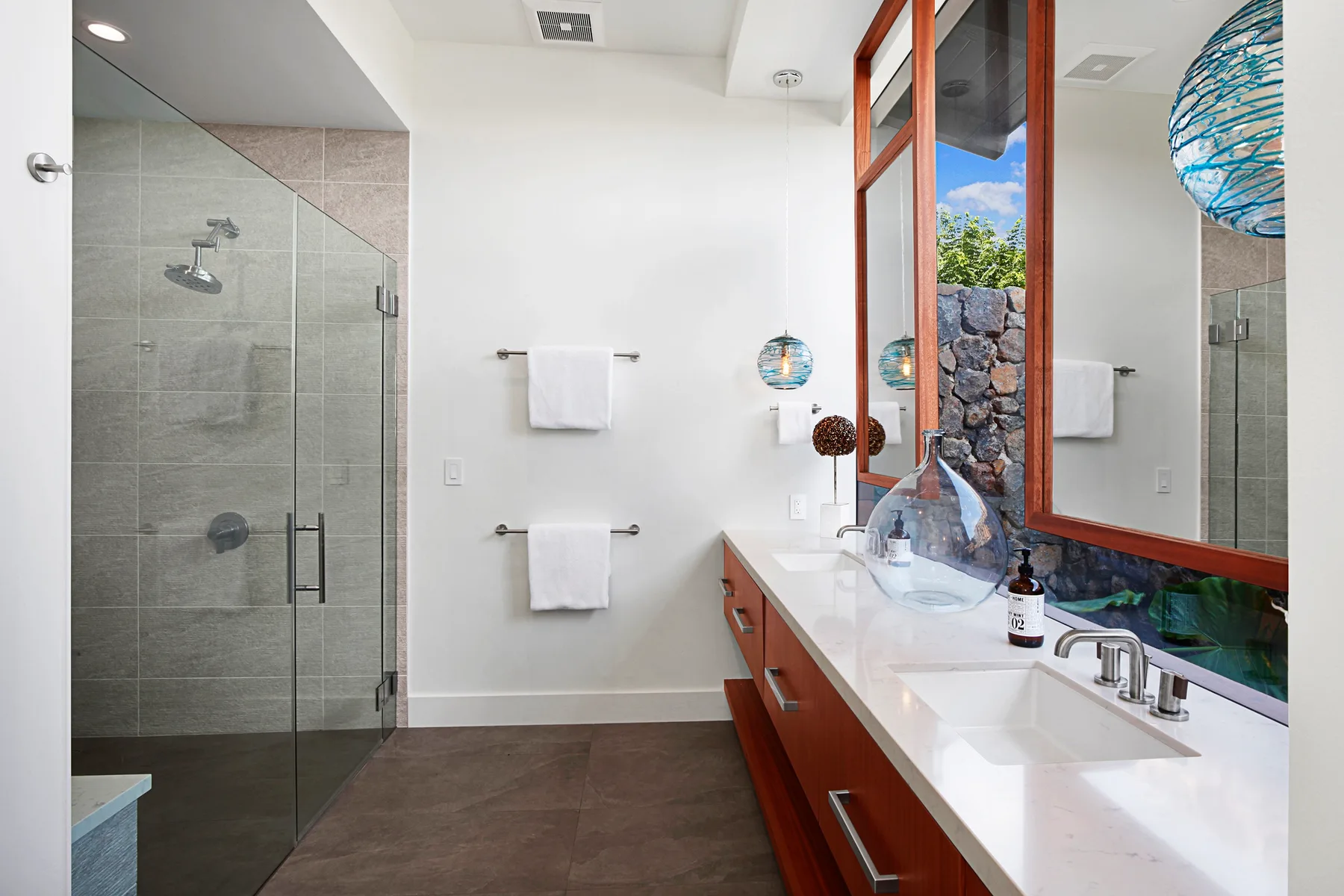 Un baño moderno con una ducha de vidrio y un tocador largo.