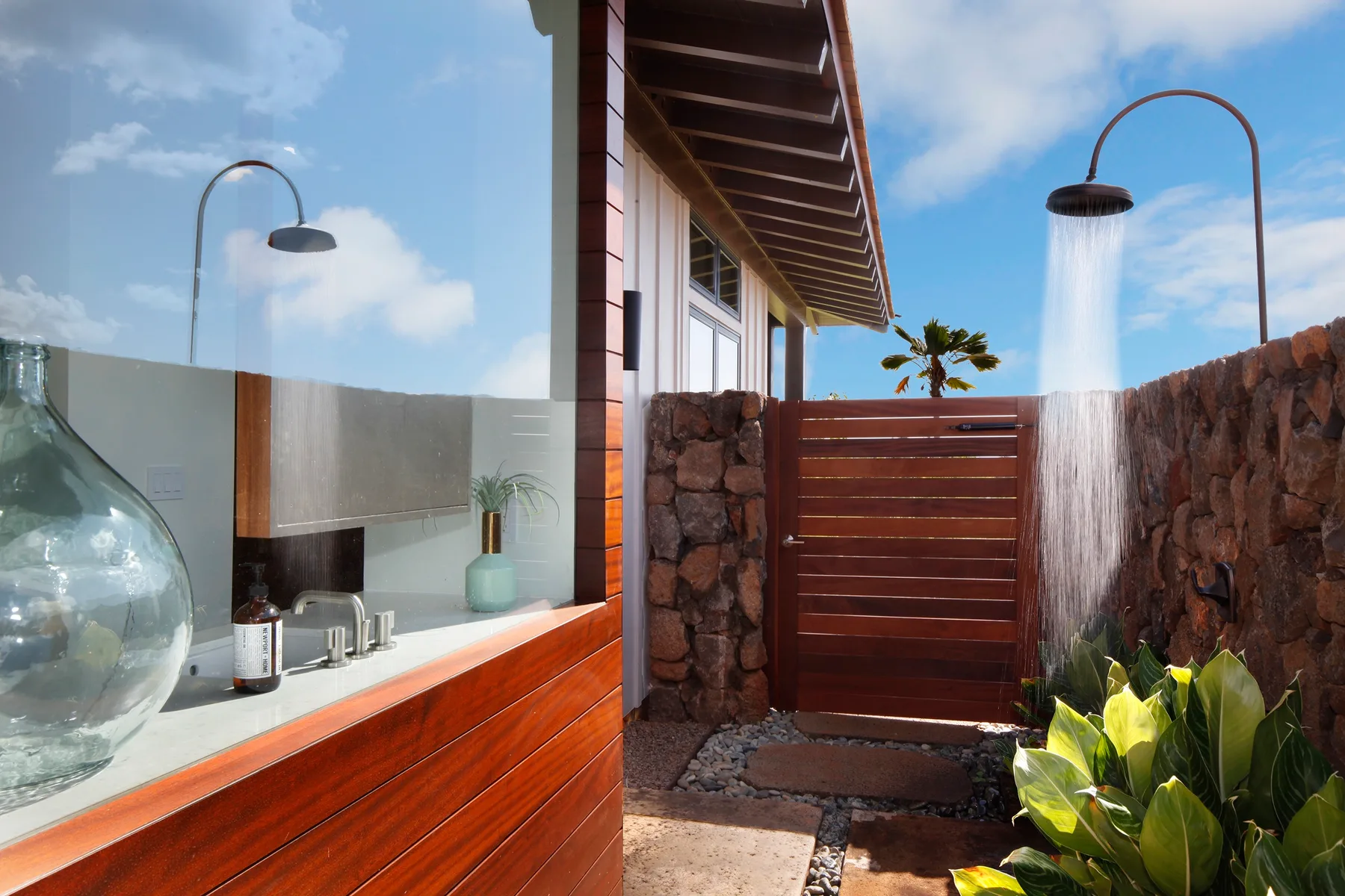 Una ducha exterior junto a una pantalla de madera y muros de piedra.