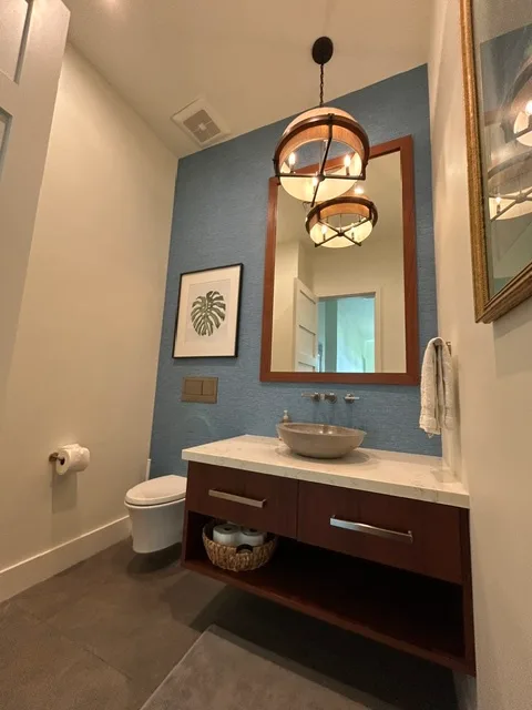 Un tocador de baño con lavabo está bajo un espejo grande en una pared azul.