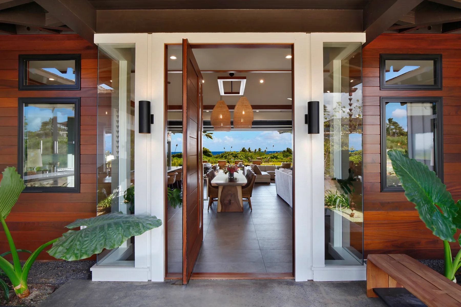 Una entrada abierta conduce a un comedor luminoso con una mesa y luces colgantes.