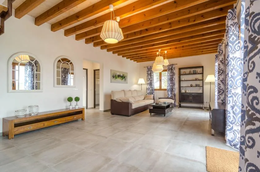 Una sala de estar amplia con asientos, una mesa baja y vigas de madera a la vista.