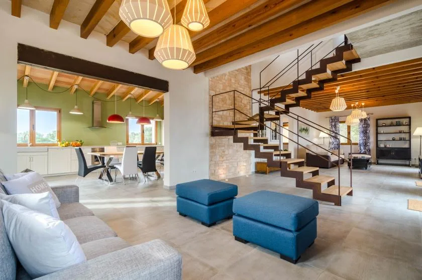 Una amplia sala de estar con otomanas azules y una escalera abierta.