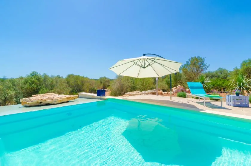Una piscina con una sombrilla grande y una tumbona al lado.