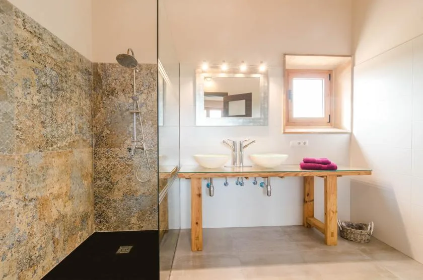 Un baño luminoso con lavabo doble y ducha a ras de suelo.
