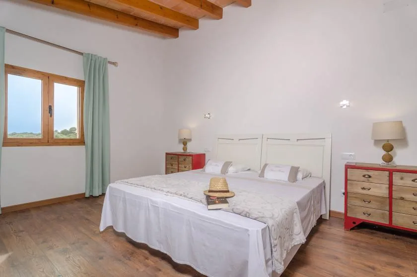 Un dormitorio con una cama doble, mesitas de noche y una ventana con cortinas.