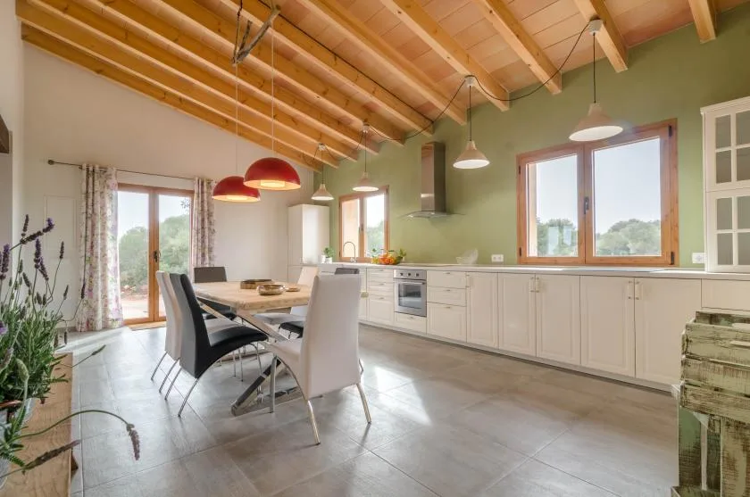 Comedor junto a una cocina, con una mesa y ventanas grandes.