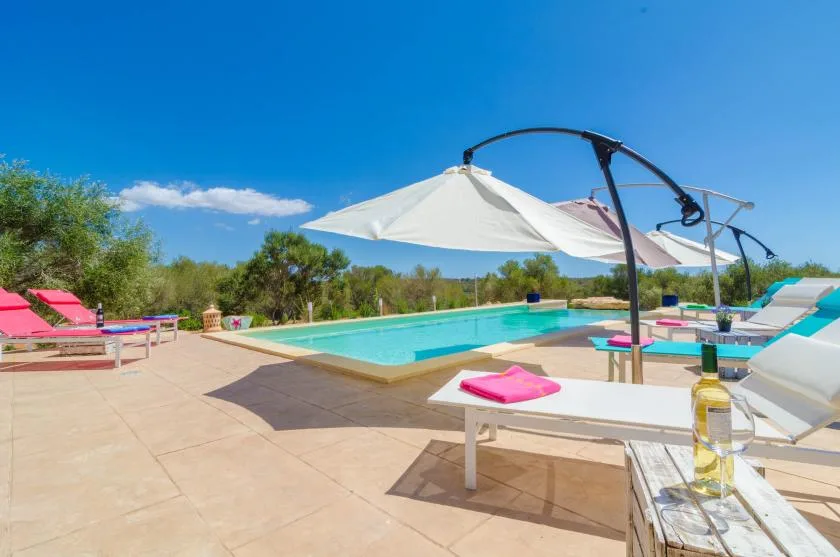 Una zona de piscina al aire libre con tumbonas y una gran sombrilla blanca.