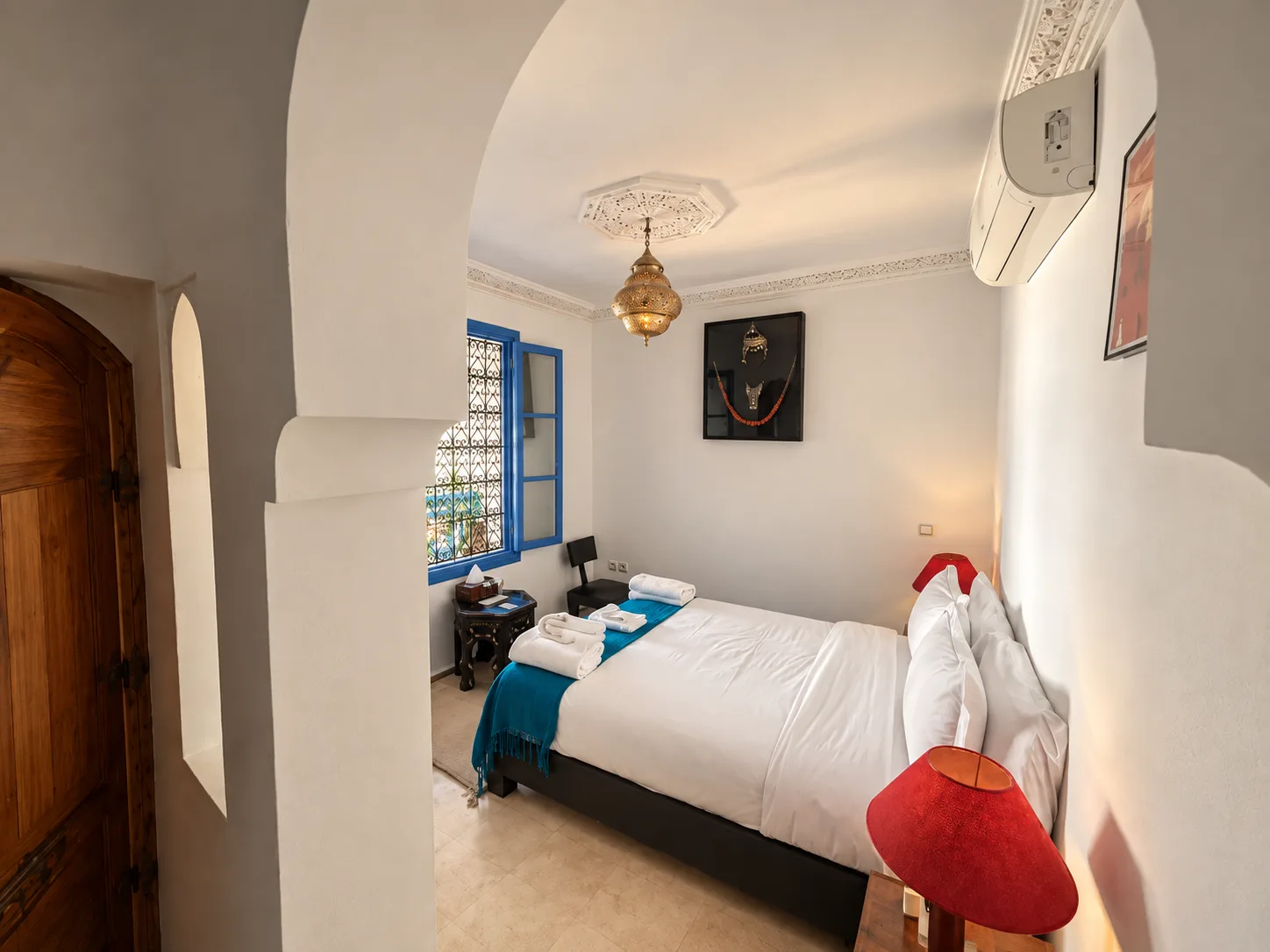 Dormitorio con ropa de cama blanca y una manta decorativa azul