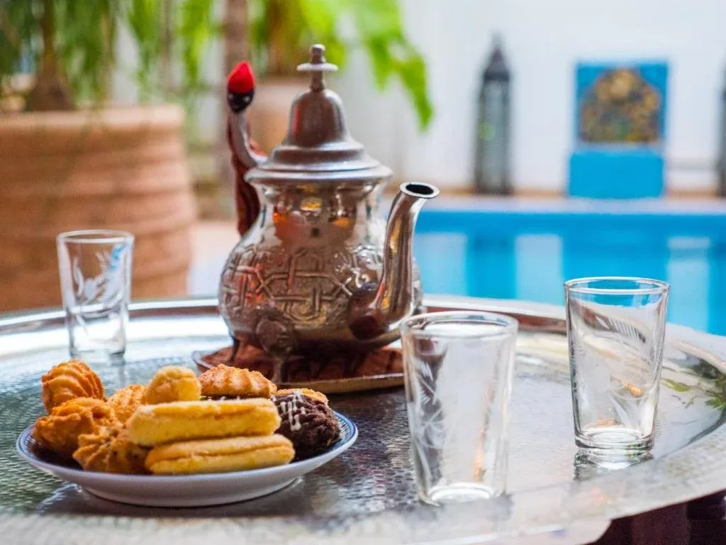 Bandeja de té con vasos y galletas junto a la piscina del patio
