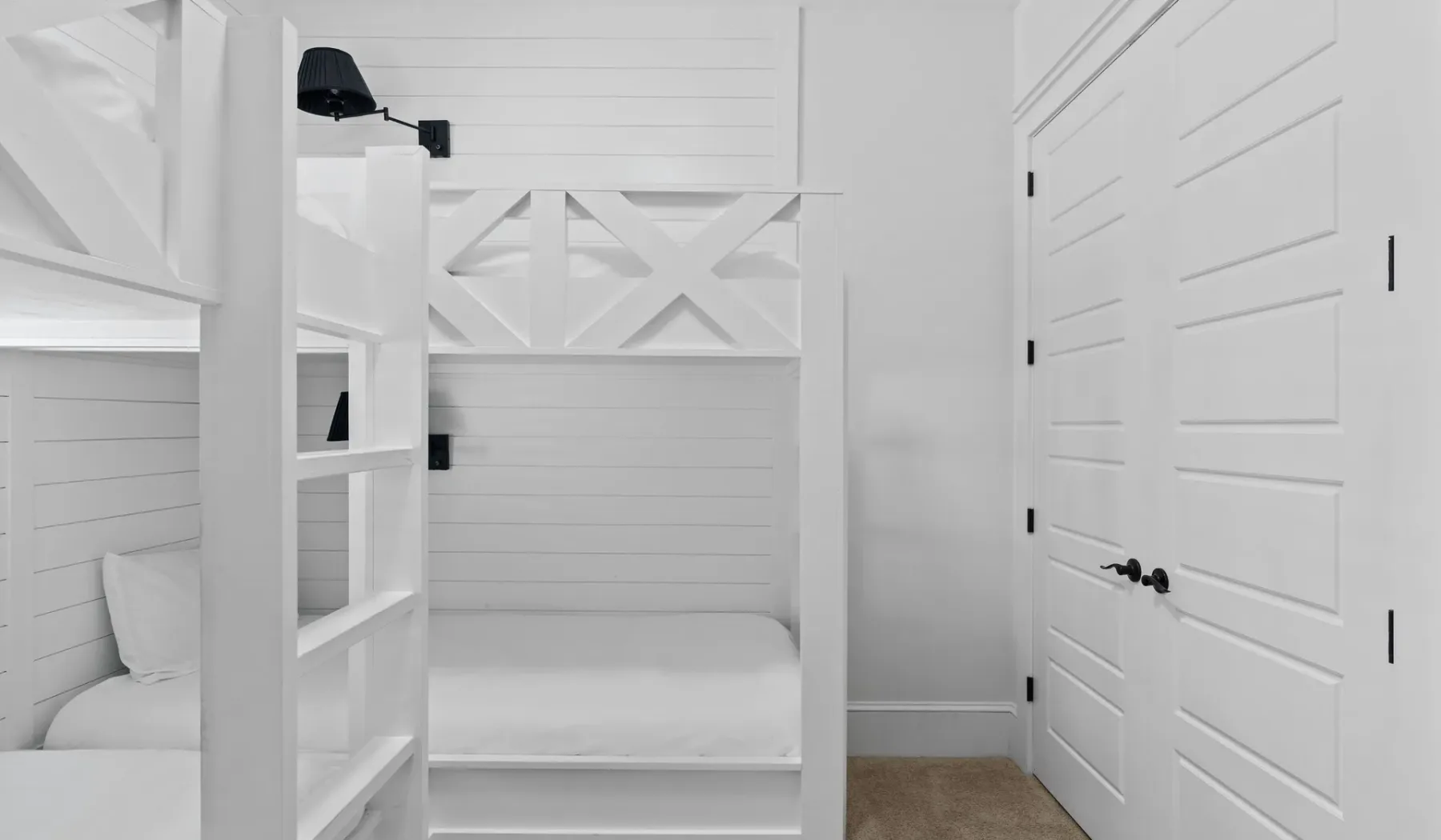 Una litera blanca está en un dormitorio luminoso con paredes revestidas.