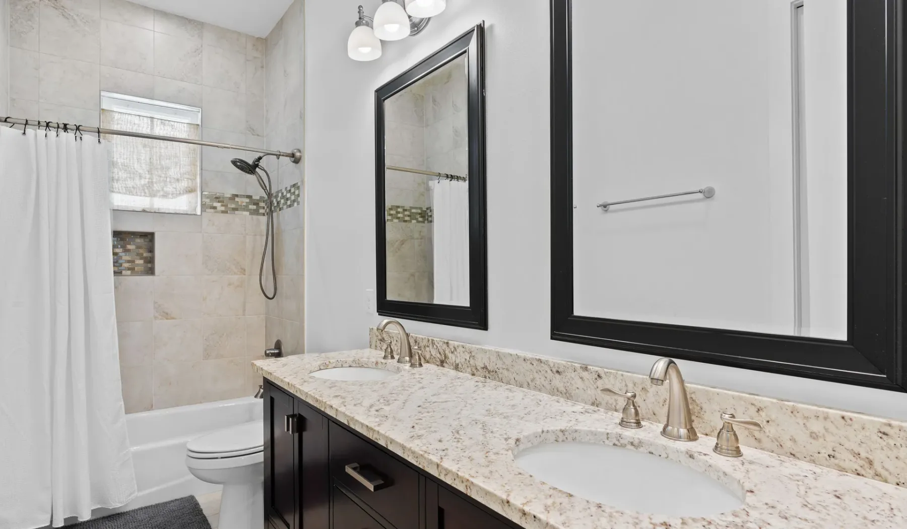 Un baño con tocador de doble lavabo, espejo grande y bañera.