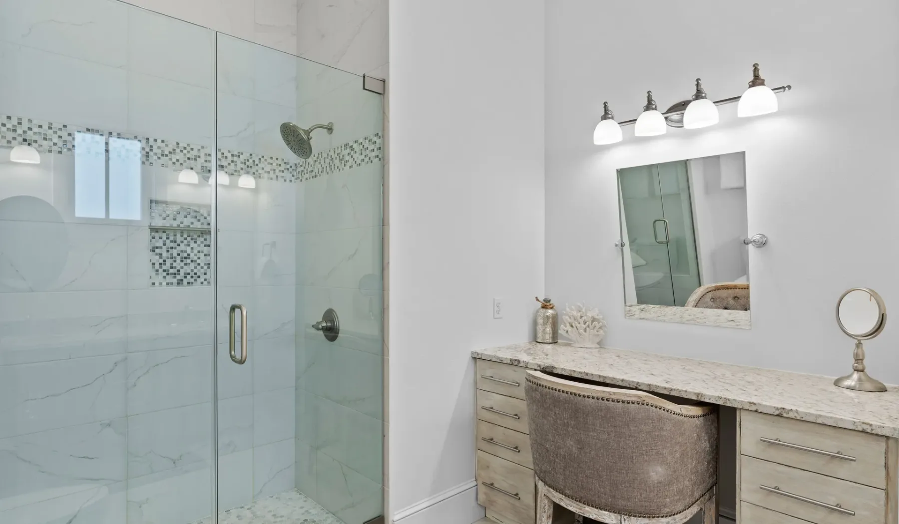Un baño luminoso con una ducha de vidrio y un tocador.