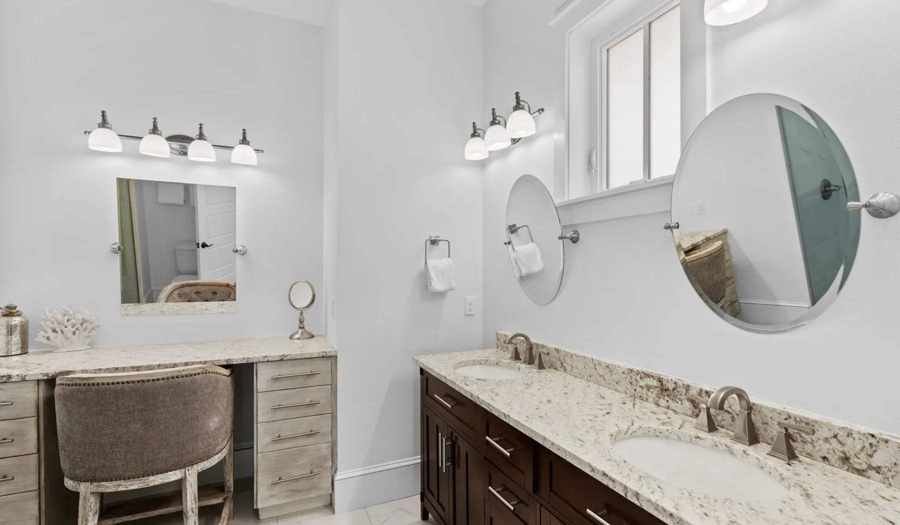 Un baño luminoso tiene tocadores largos, espejos y luces en la pared.