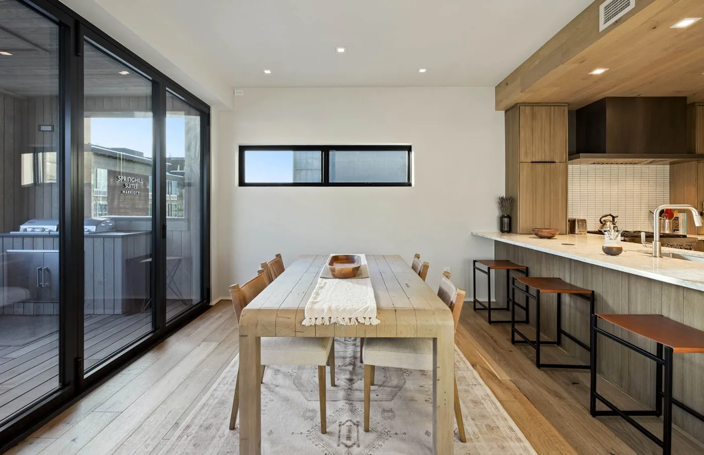 Un comedor con una larga mesa de madera junto a una cocina abierta.