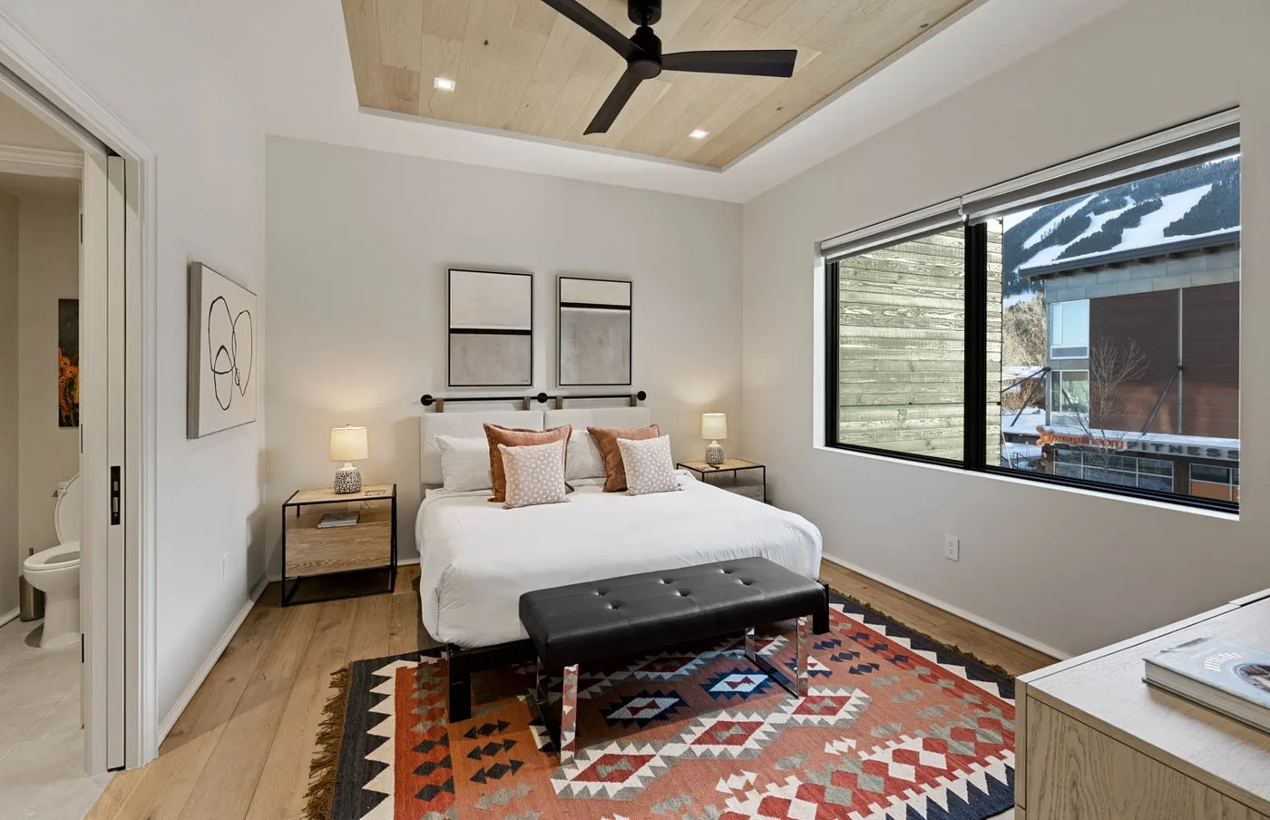 Un dormitorio con una cama, un banco y una ventana grande.
