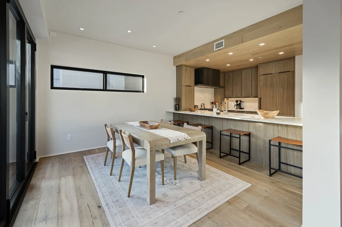 Comedor con una mesa de madera y una cocina abierta al fondo.