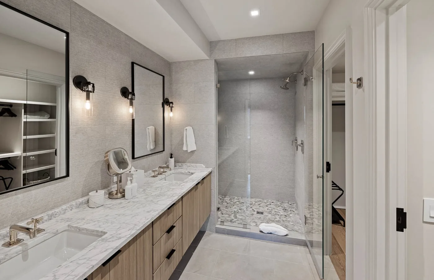 Un baño con un tocador largo y una ducha con mampara de vidrio.
