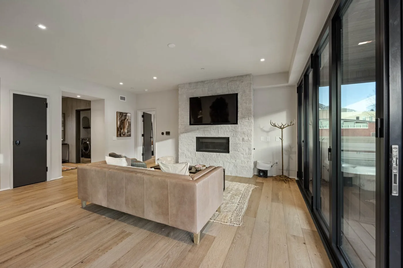 Una sala luminosa con zona de estar, chimenea y grandes puertas de vidrio.