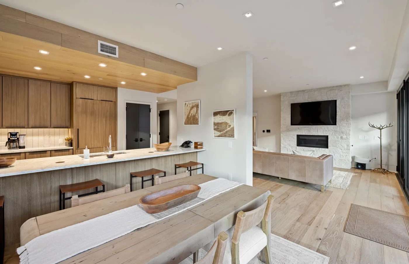 An open-plan dining and living area with a long wooden table and kitchen counter.