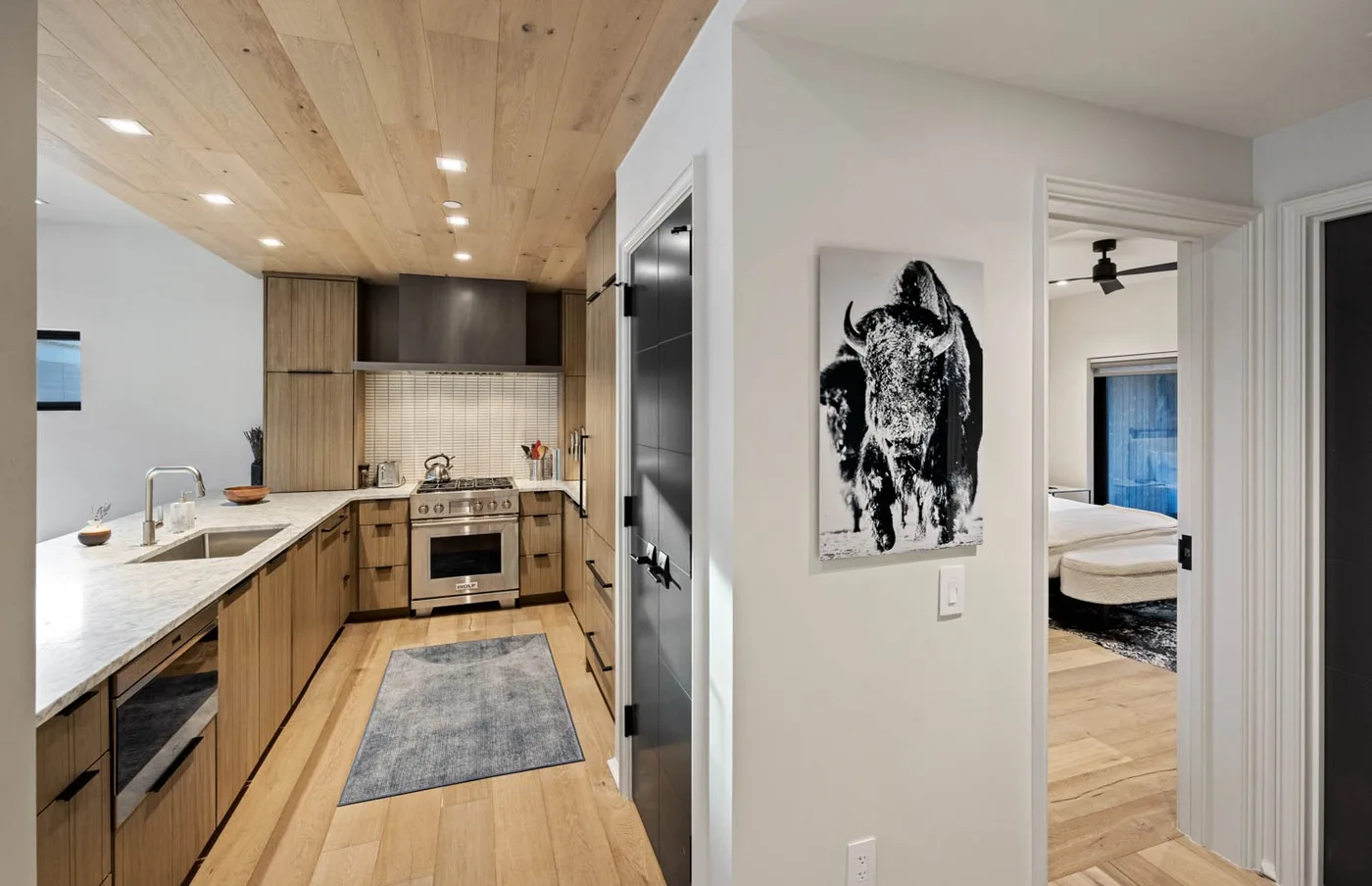 Una cocina moderna con gabinetes de madera se abre a una habitación luminosa.