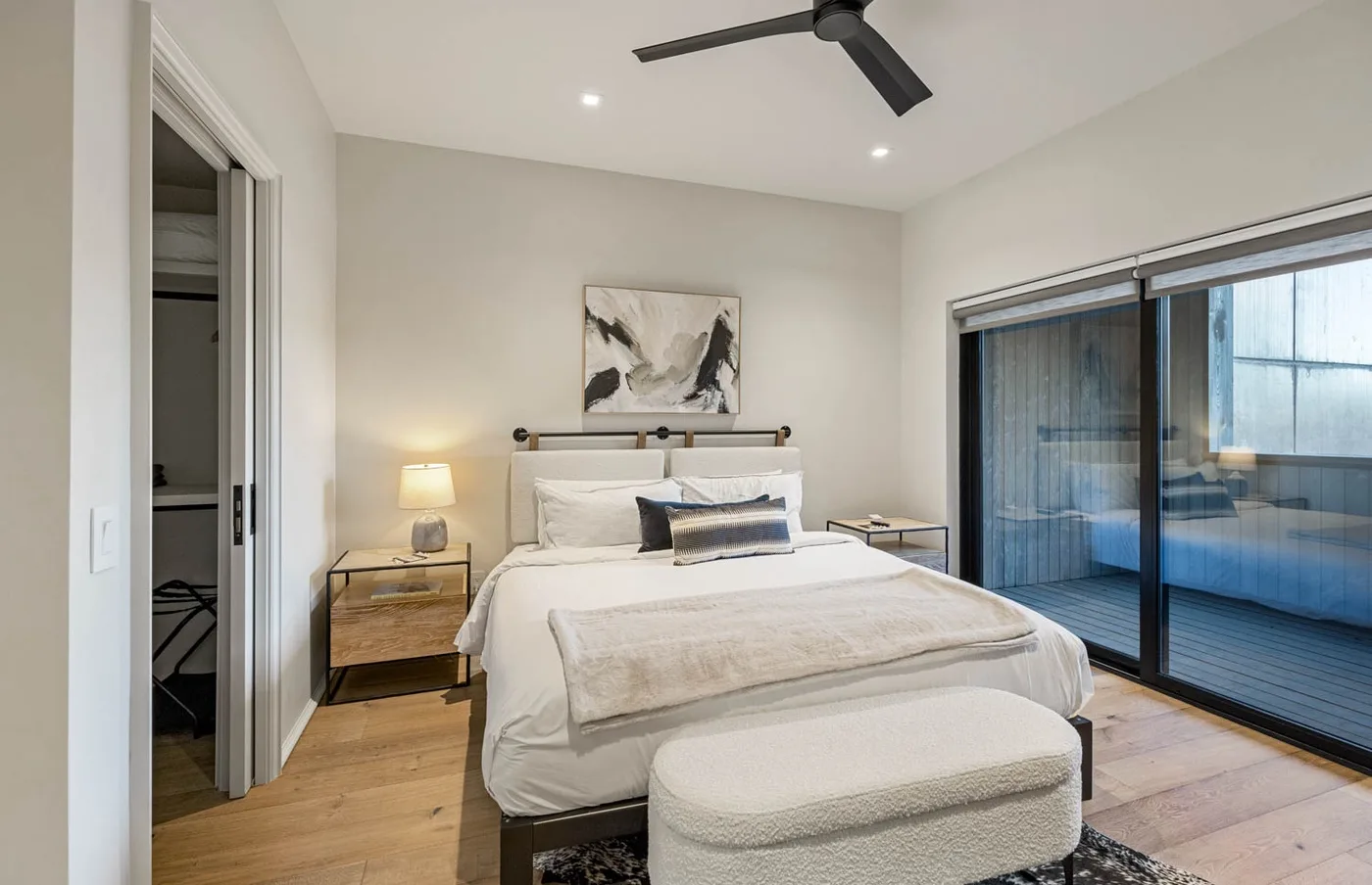 Un dormitorio luminoso con una cama tendida y puertas corredizas de vidrio.